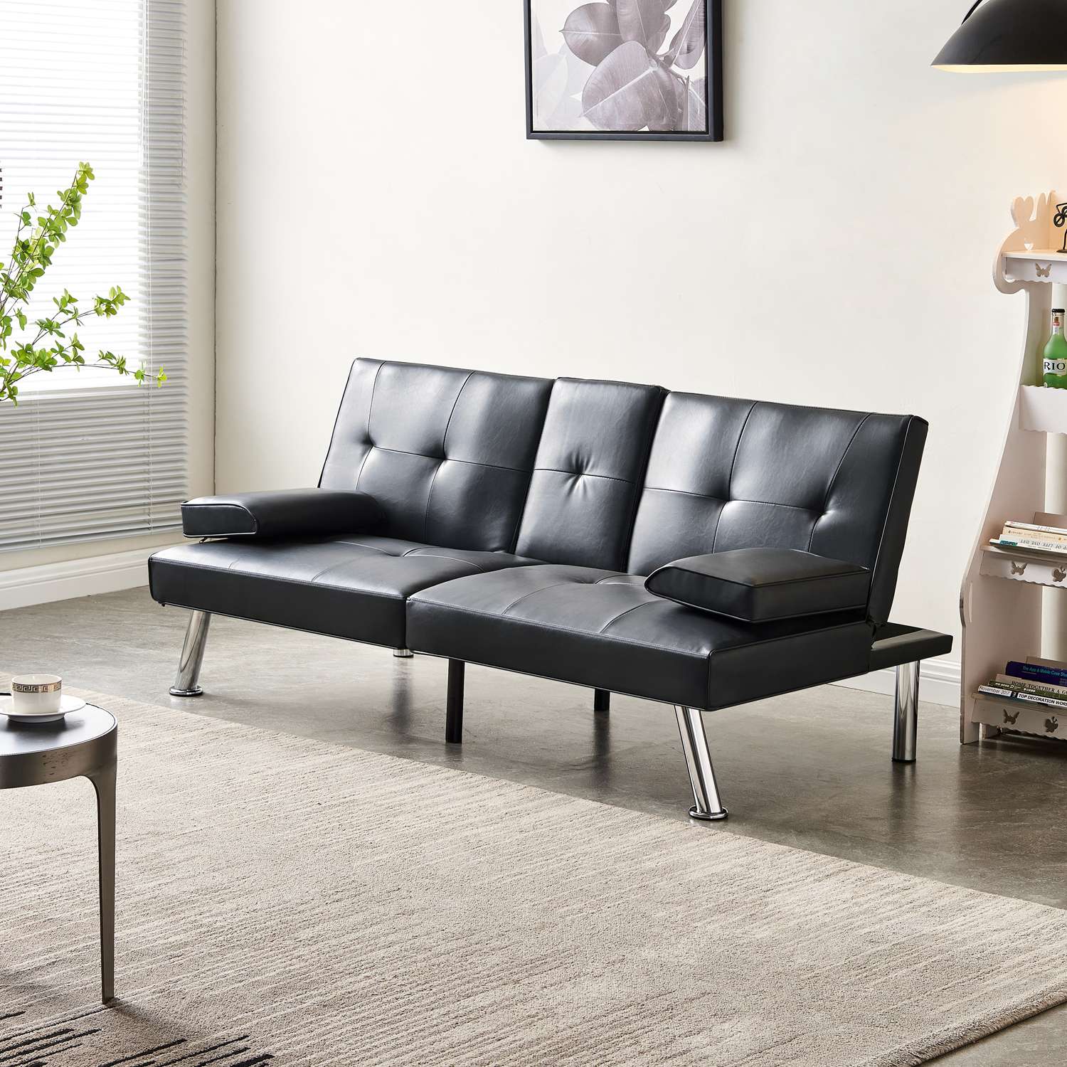 Black faux leather sofa bed in a living room setting with a rug and small table.