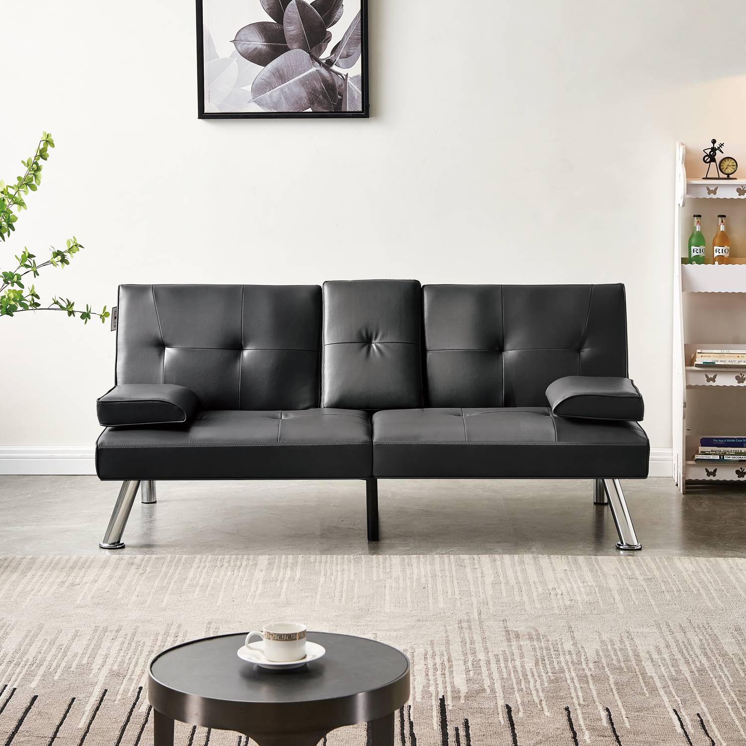 Black faux leather sofa bed in a living room setting with a small round table and decor items.