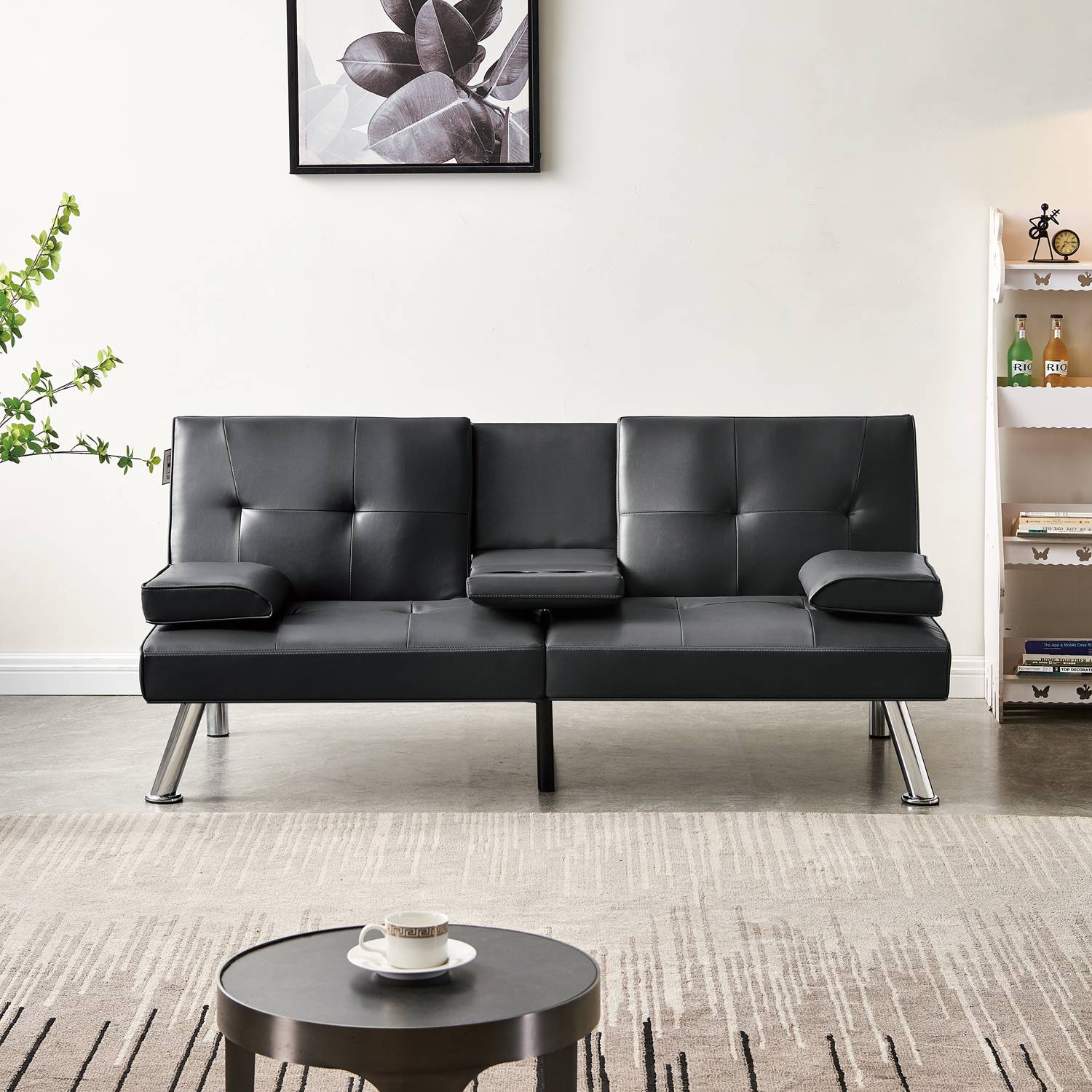 Black faux leather sofa bed in a living room setting with a coffee table and decorative items.