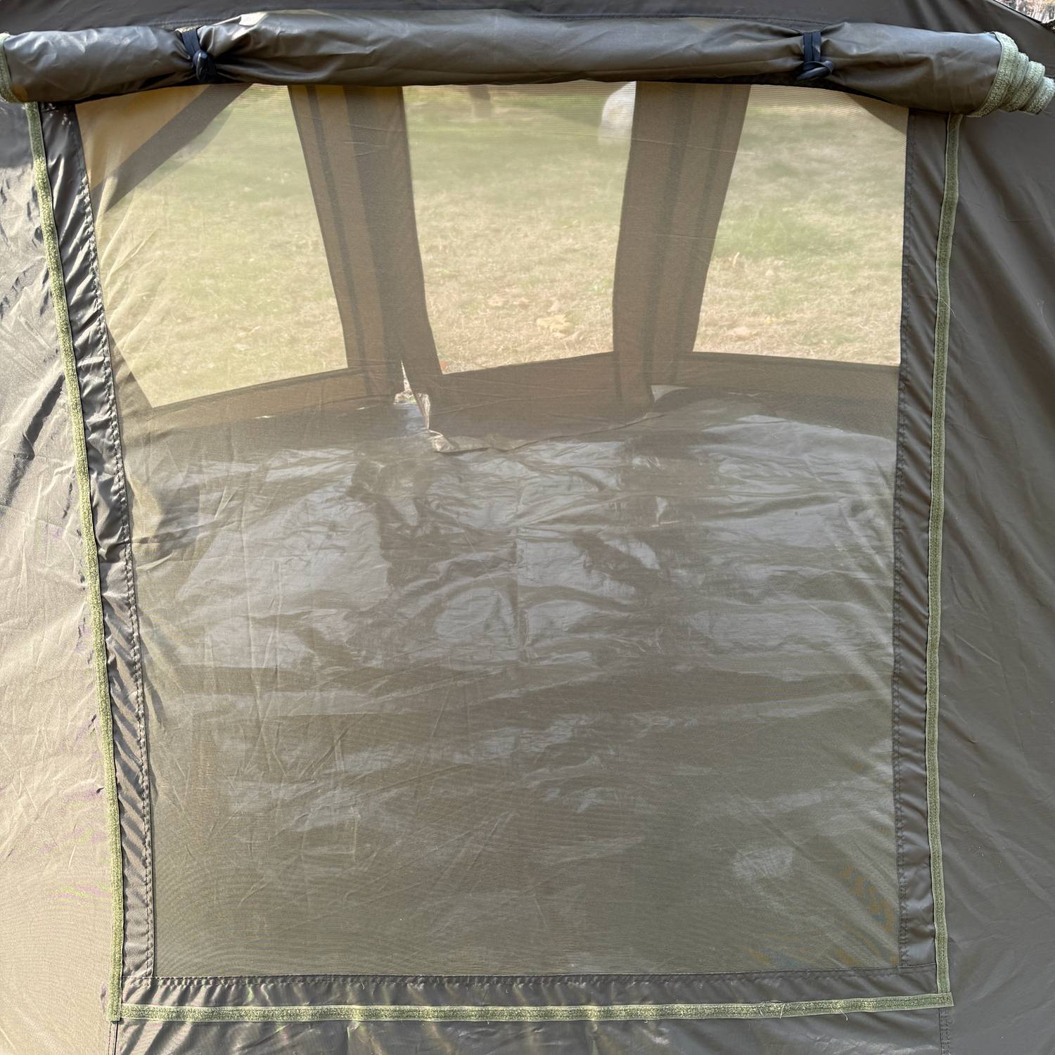 Fishing bivvy with mesh walls and a tarp on the ground