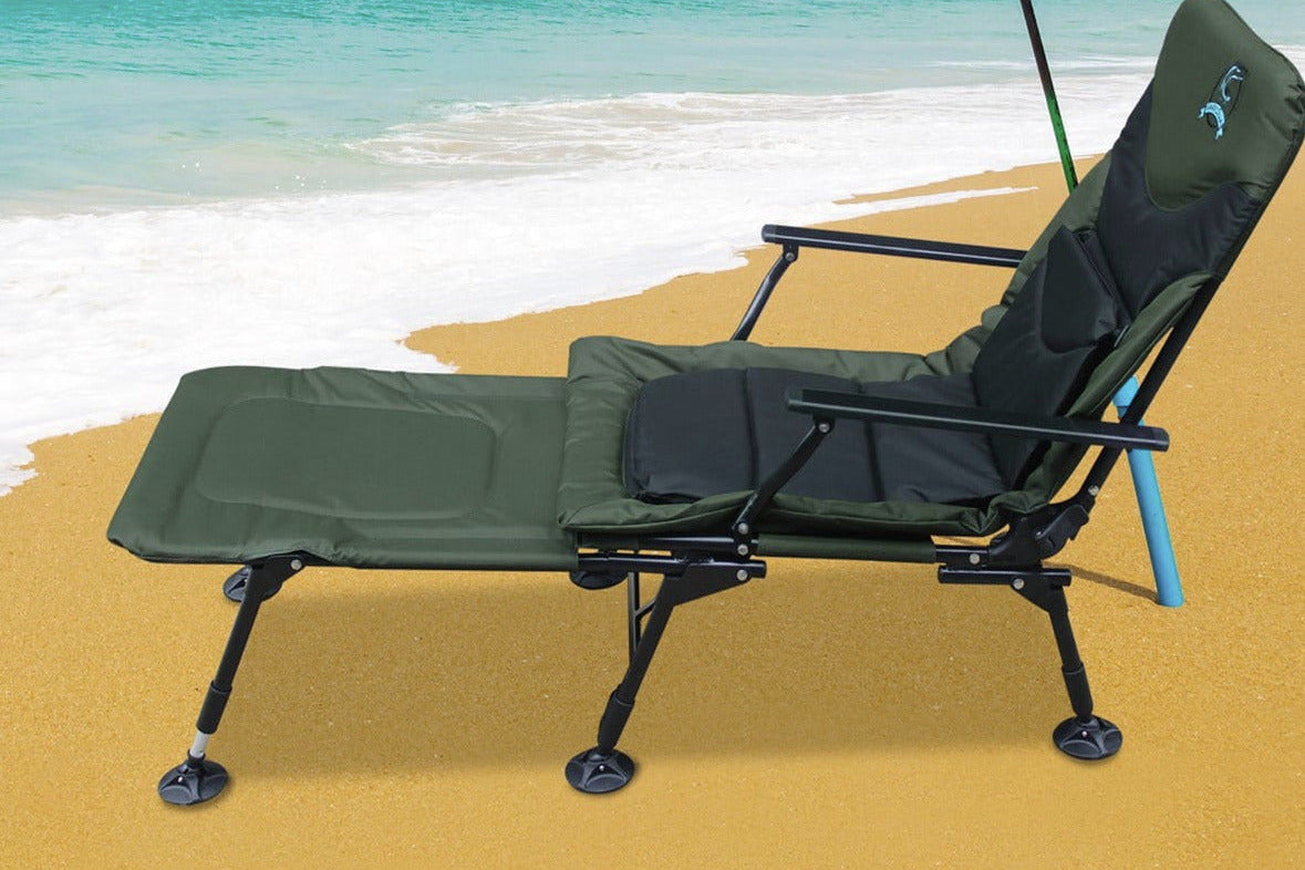Green fishing chair on a sandy beach with ocean and mountain in the background