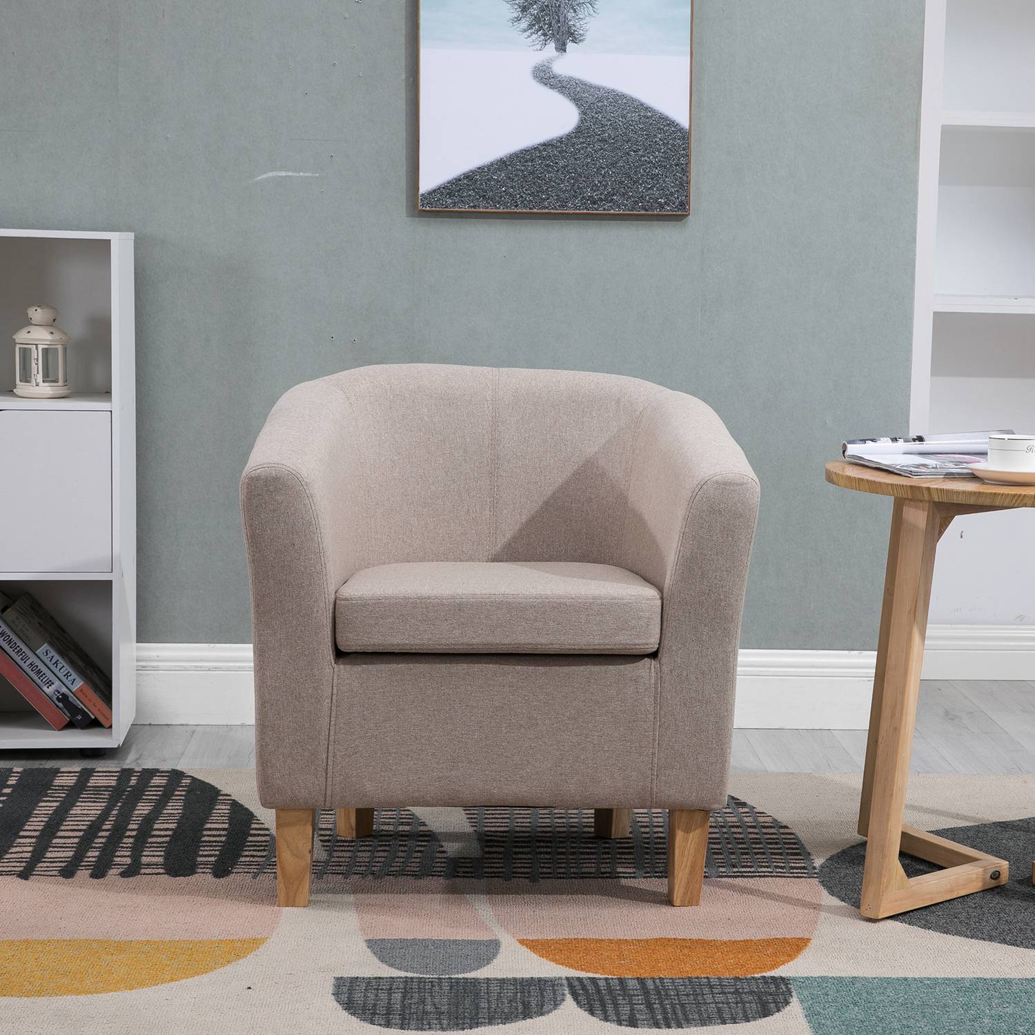 Cream tub chair in a living room setting with a rug and wall art.