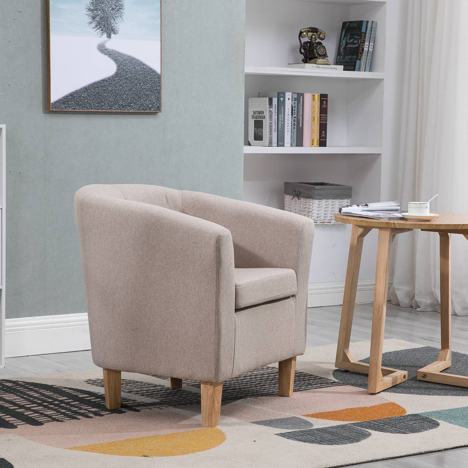 Cream tub chair in a living room setting with a bookshelf and small table.