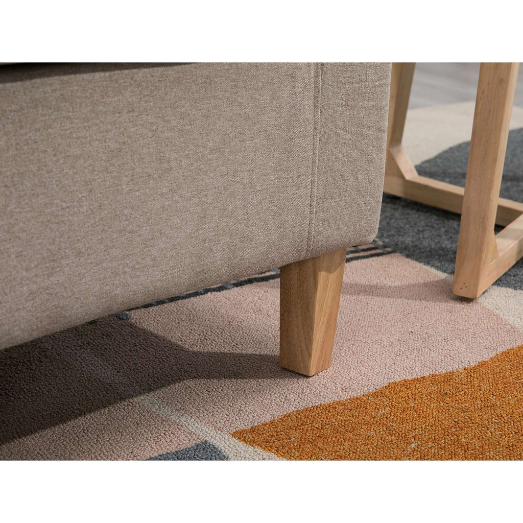 Close-up of a textured cream tub chair with wooden legs on a patterned rug.