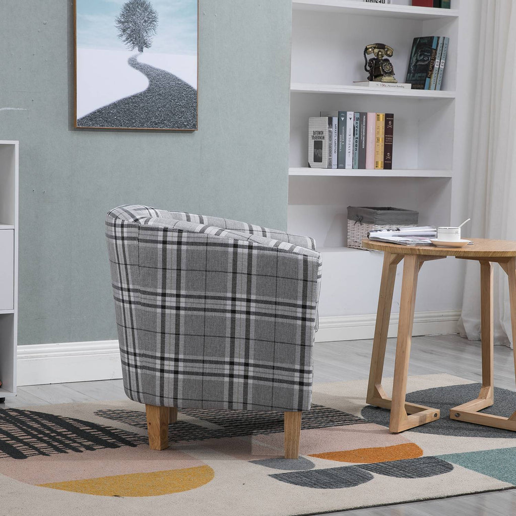 grey checkered tub chair in a room with a bookshelf and wooden table.