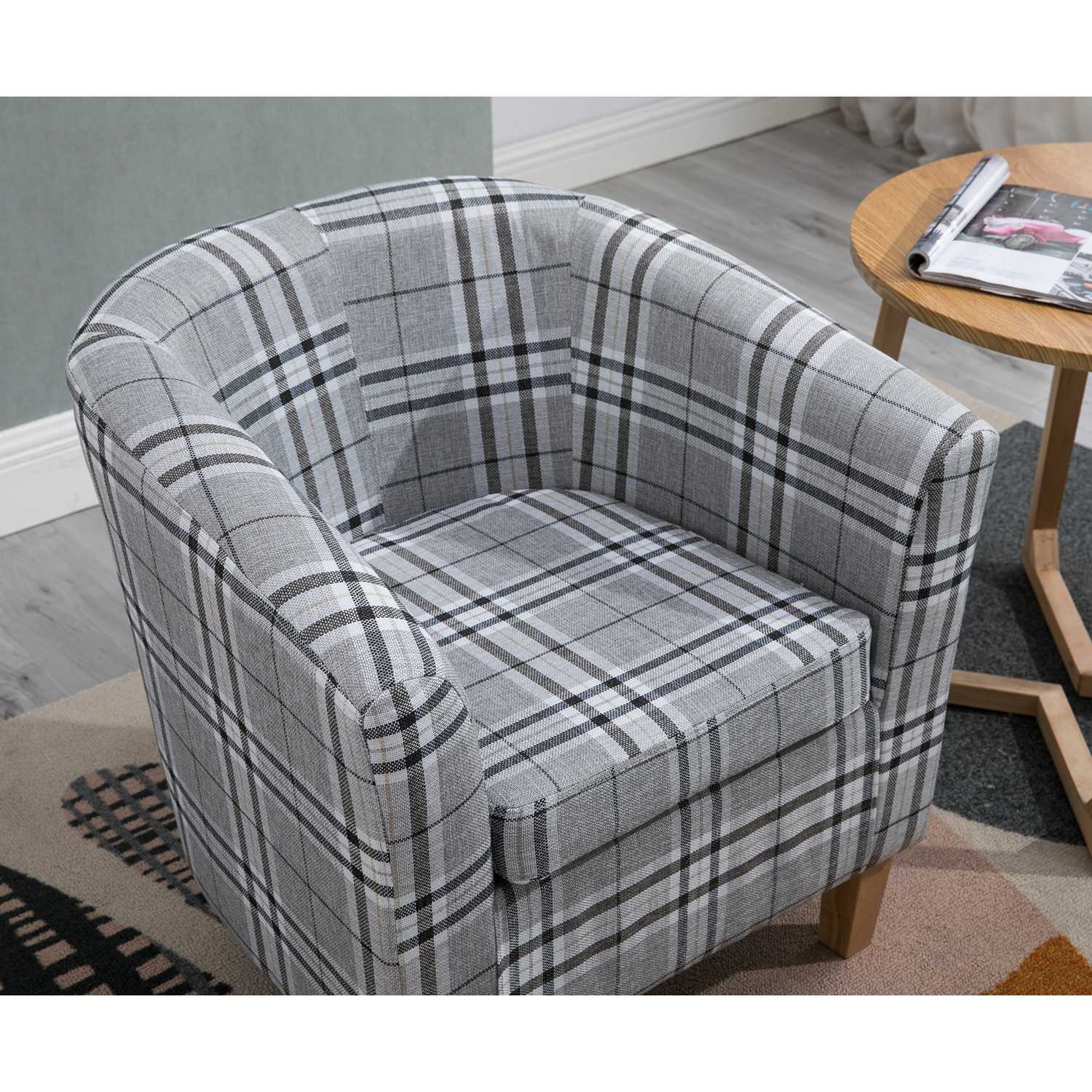 Grey checkered tub chair in a room with a wooden table and magazine.