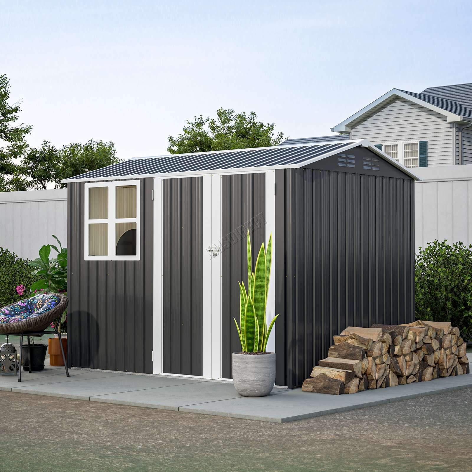 Anthracite metal garden shed with an apex roof and a white window in a garden setting including a potted plant and stack of firewood.