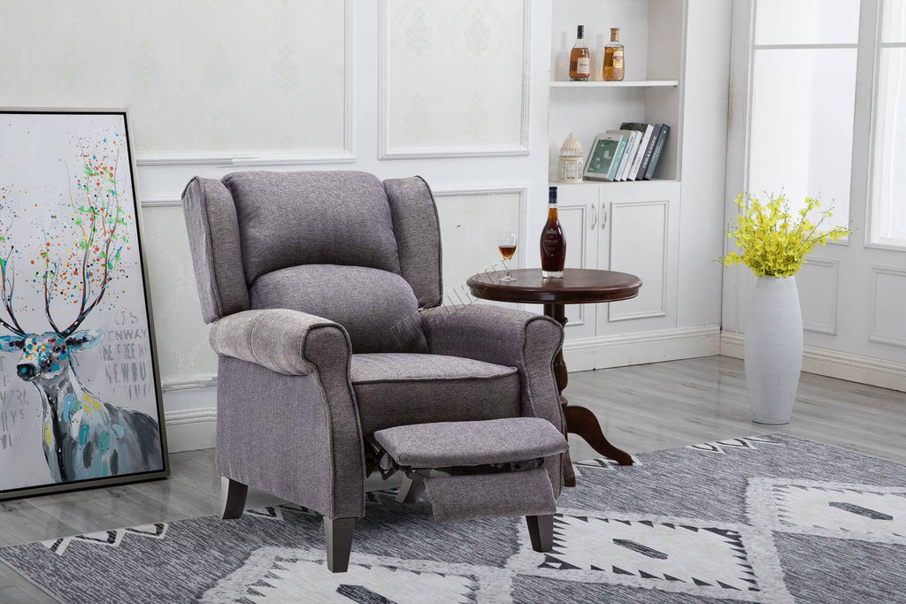 Grey recliner chair in a living room setting with a rug, table, and wall art.