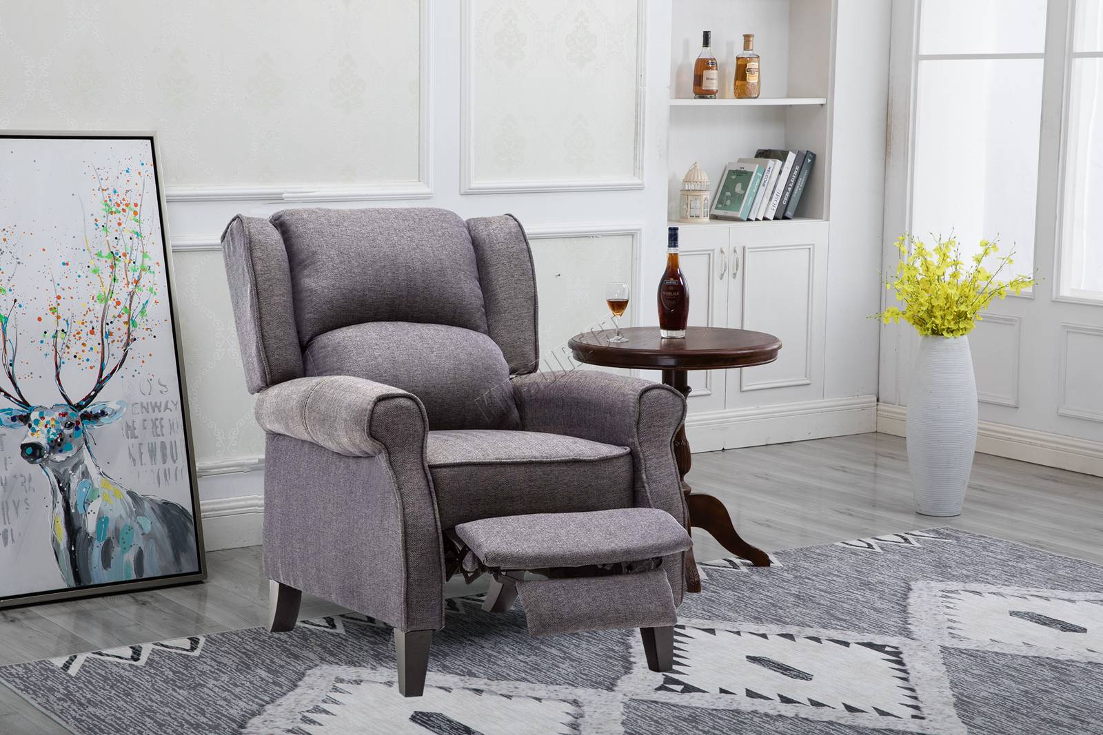 Grey recliner chair in a living room setting with a rug, table, and wall art.