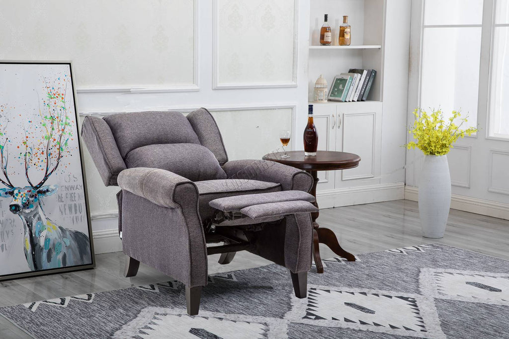 Grey recliner armchair in a living room setting with a rug, table, and decorative items.