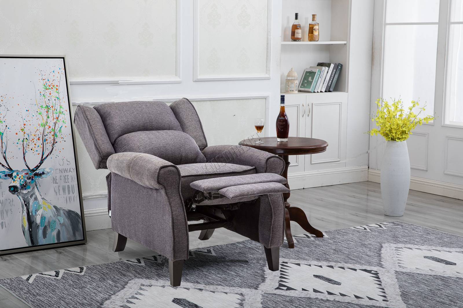 Grey recliner armchair in a living room setting with a rug, table, and decorative items.