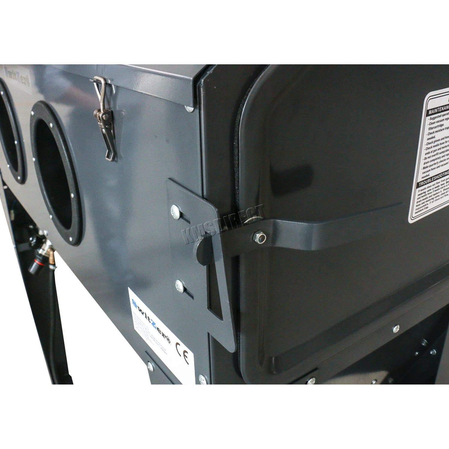 Close-up of a black metal sandblasting machine with cylindrical components and visible branding on a white background.