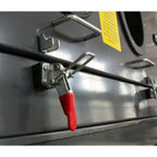 Metal latch with red handle on a metallic surface from a sandblasting machine