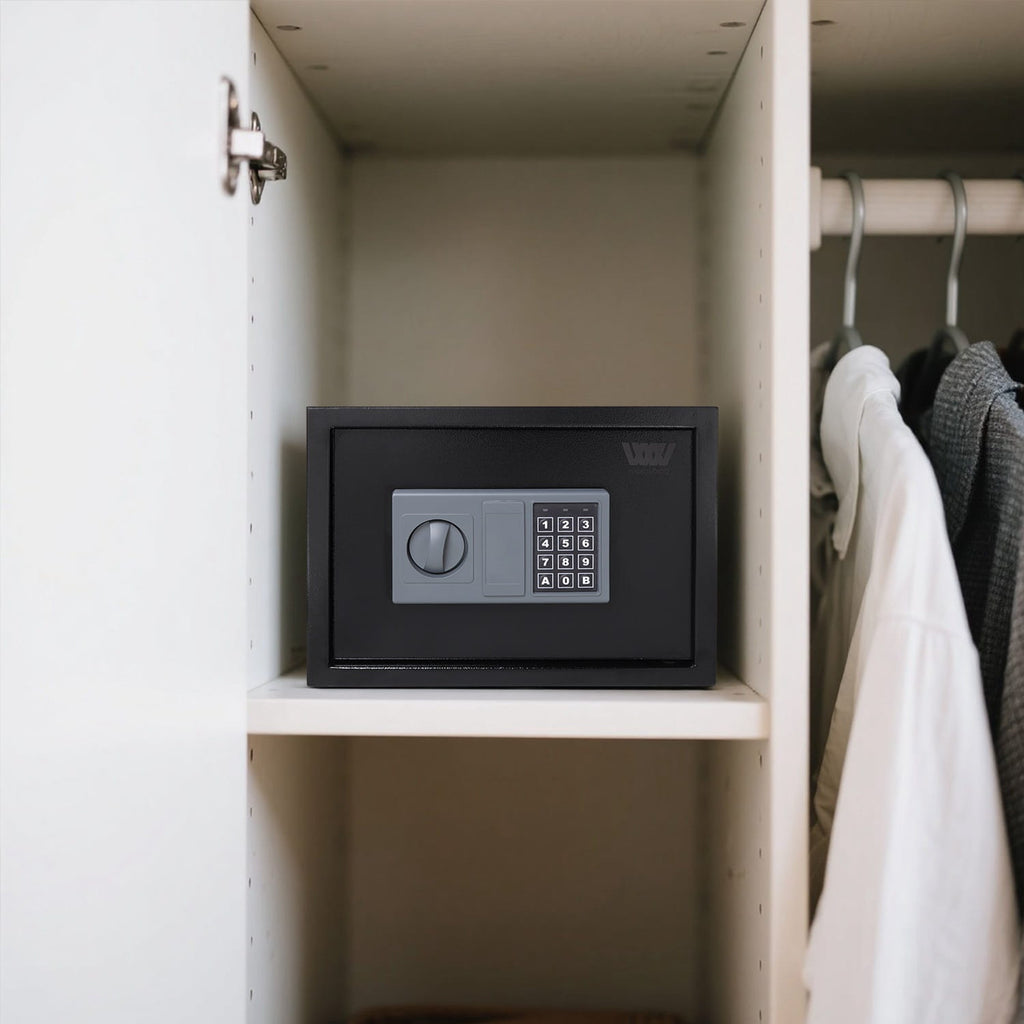 Black security safe box on a shelf in a closet with clothes hanging on a rack.