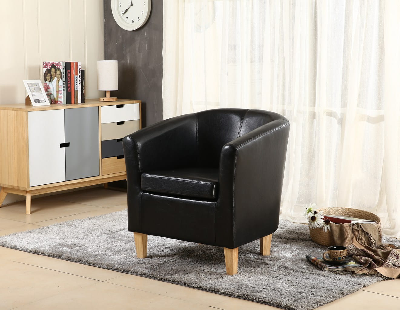 Black faux leather armchair in a living room setting with a cabinet and decor items.