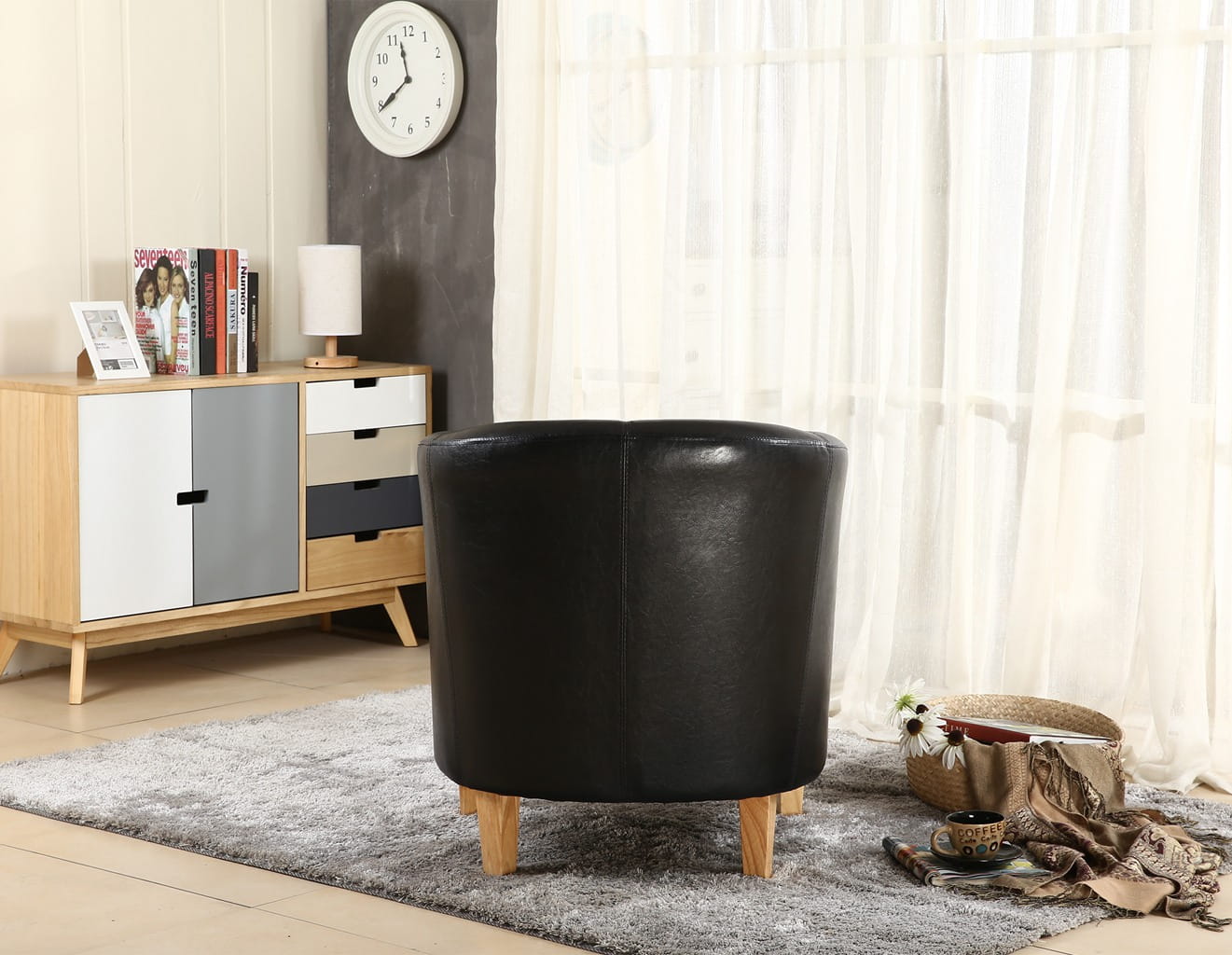 Black faux leather armchair in a living room setting with a sideboard and clock.