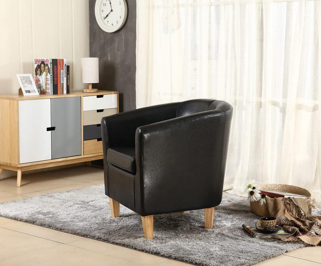 Black faux leather armchair in a living room setting with a sideboard and window.