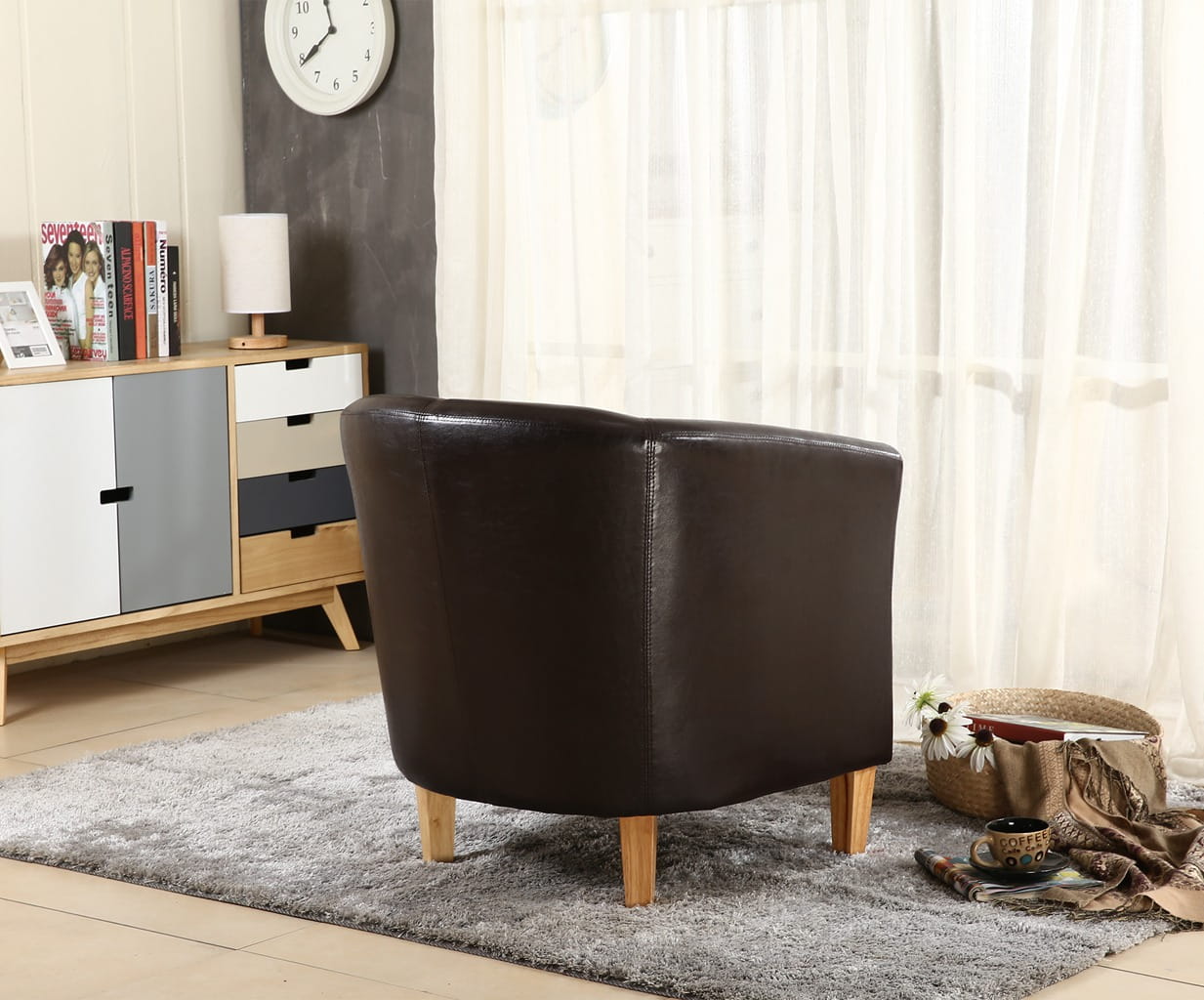 Brown faux leather armchair in a living room setting with a clock, books, and a cabinet.