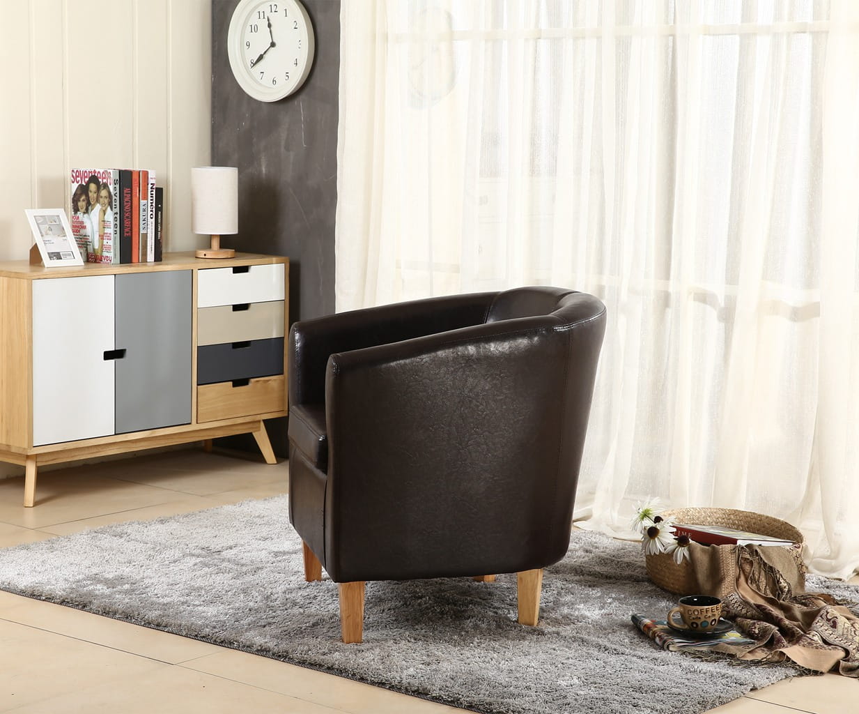 Modern living room with a brown faux leather armchair, wooden cabinet, and decorative items.