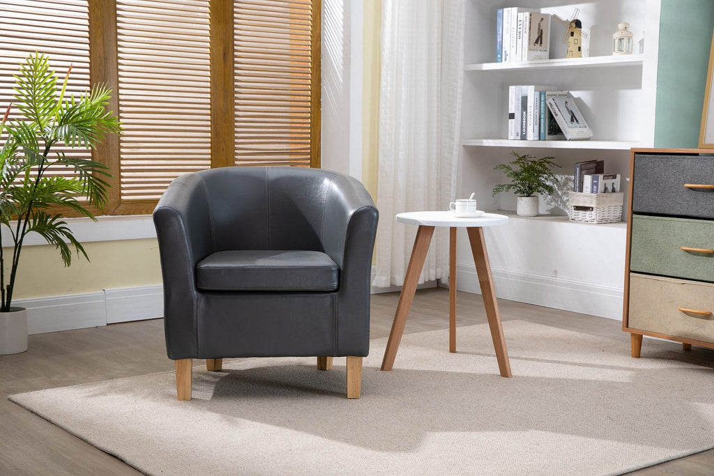 Grey faux leather armchair in a room with a small table, plants, and shelves.