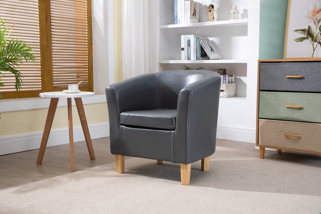 Grey faux leather armchair in a room with a small table, bookshelf, and dresser.