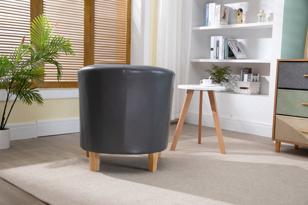 Grey faux leather armchair in a modern living room with a bookshelf and plants.