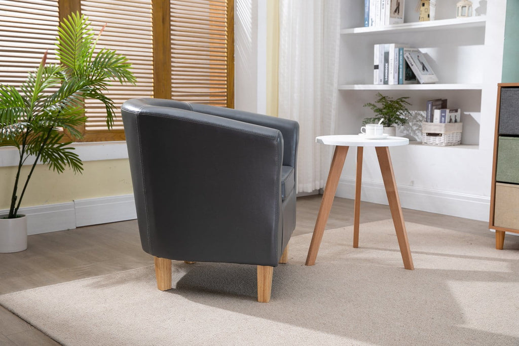 Grey faux leather armchair in a living room with a small table and bookshelf.