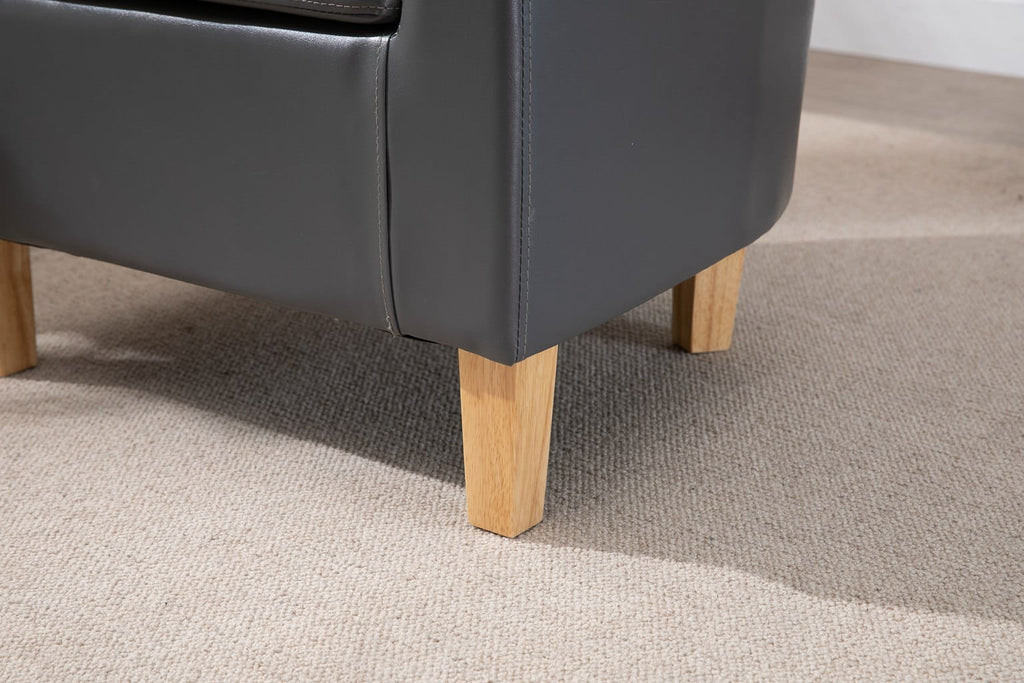 Grey faux leather armchair with wooden legs on a carpeted floor