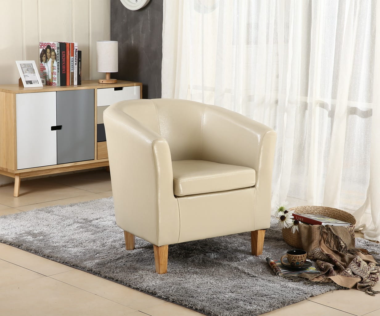Ivory faux leather armchair in a living room setting with a cabinet and curtains.