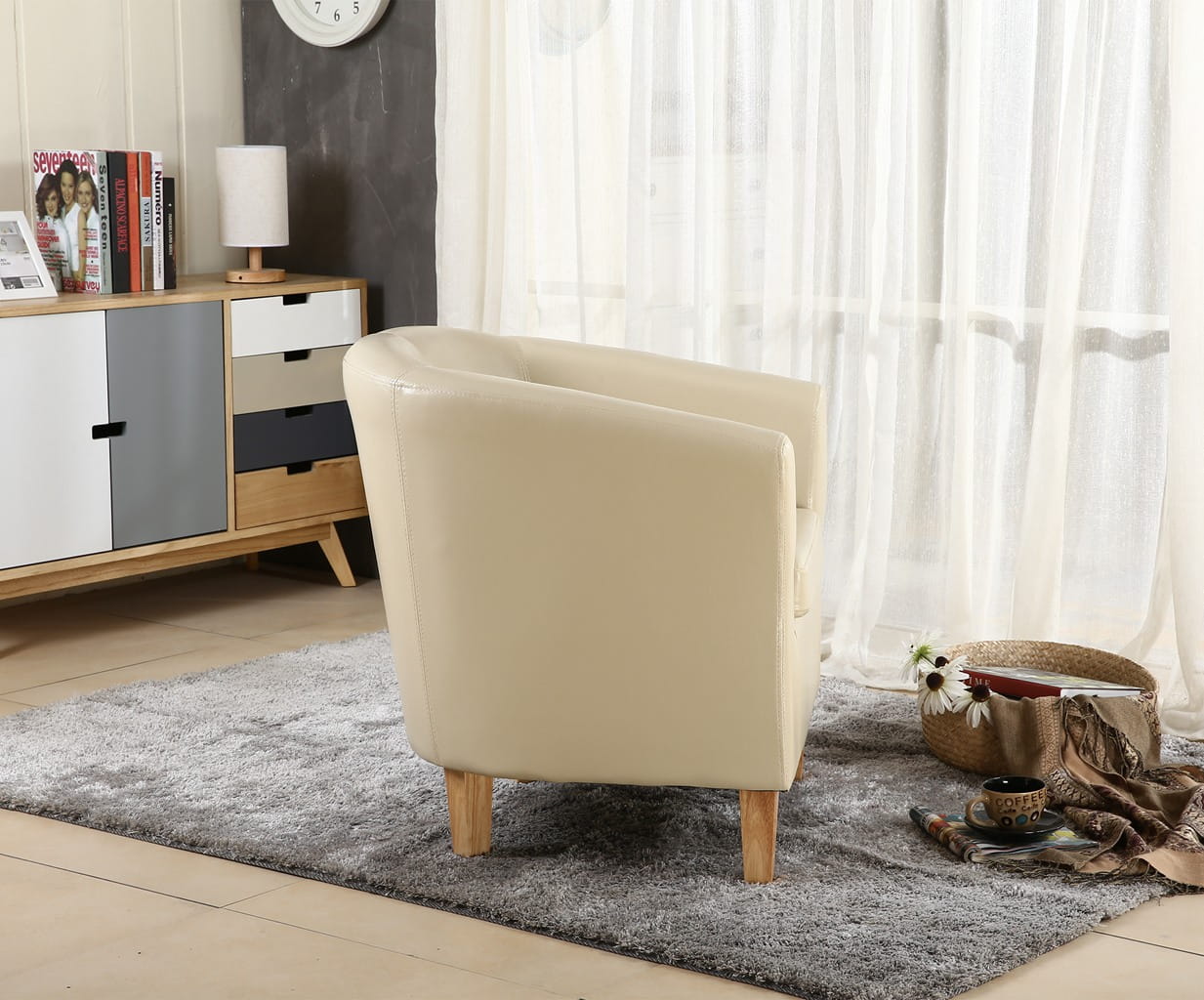 Ivory faux leather armchair in a living room setting with a sideboard and curtains.