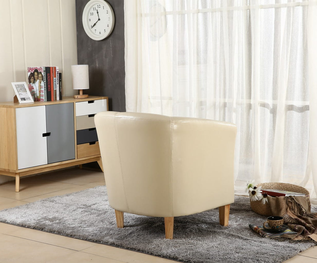 Ivory faux leather armchair in a living room with a sideboard and window in the background