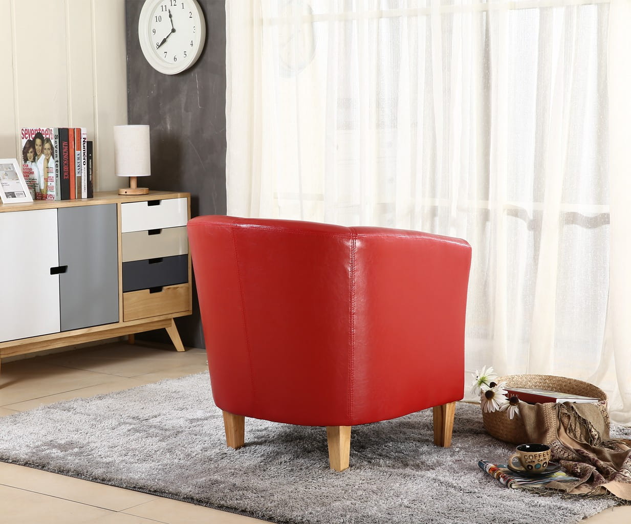 Red faux leather armchair in a living room setting with a clock on the wall and books on a shelf.