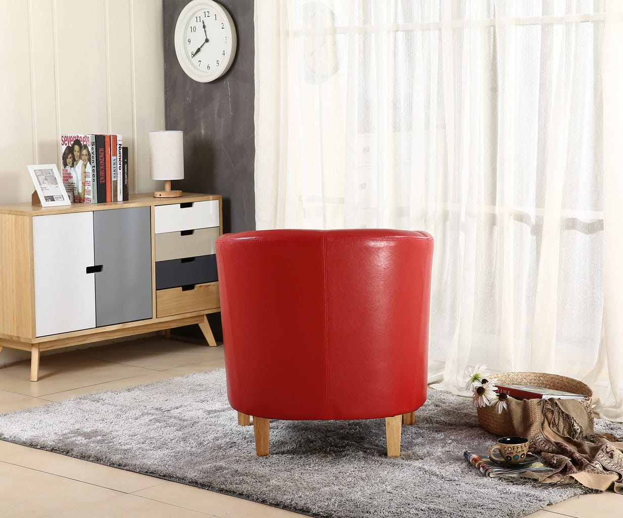 Red faux leather armchair in a room with a sideboard and clock on the wall.