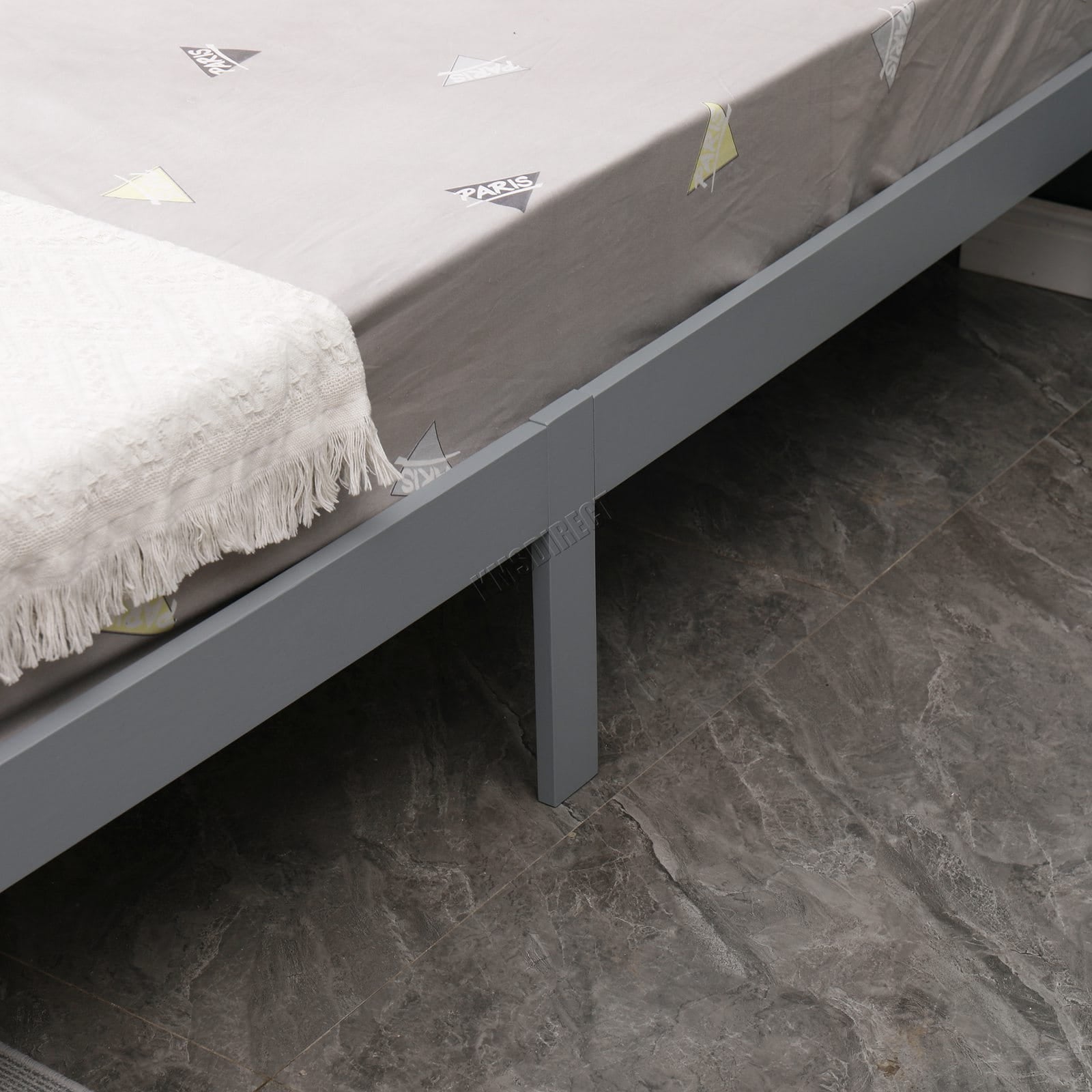 Grey bed frame with mattress on a tiled floor from the wooden double bed.