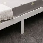 Bed with white frame and grey mattress from a wooden double bed on a dark tiled floor.