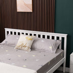 Wooden double bed with grey bedding and decorative pillows against a dark green wall.