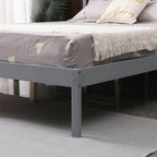 Grey wooden double bed frame with mattress and pillows in a bedroom setting.